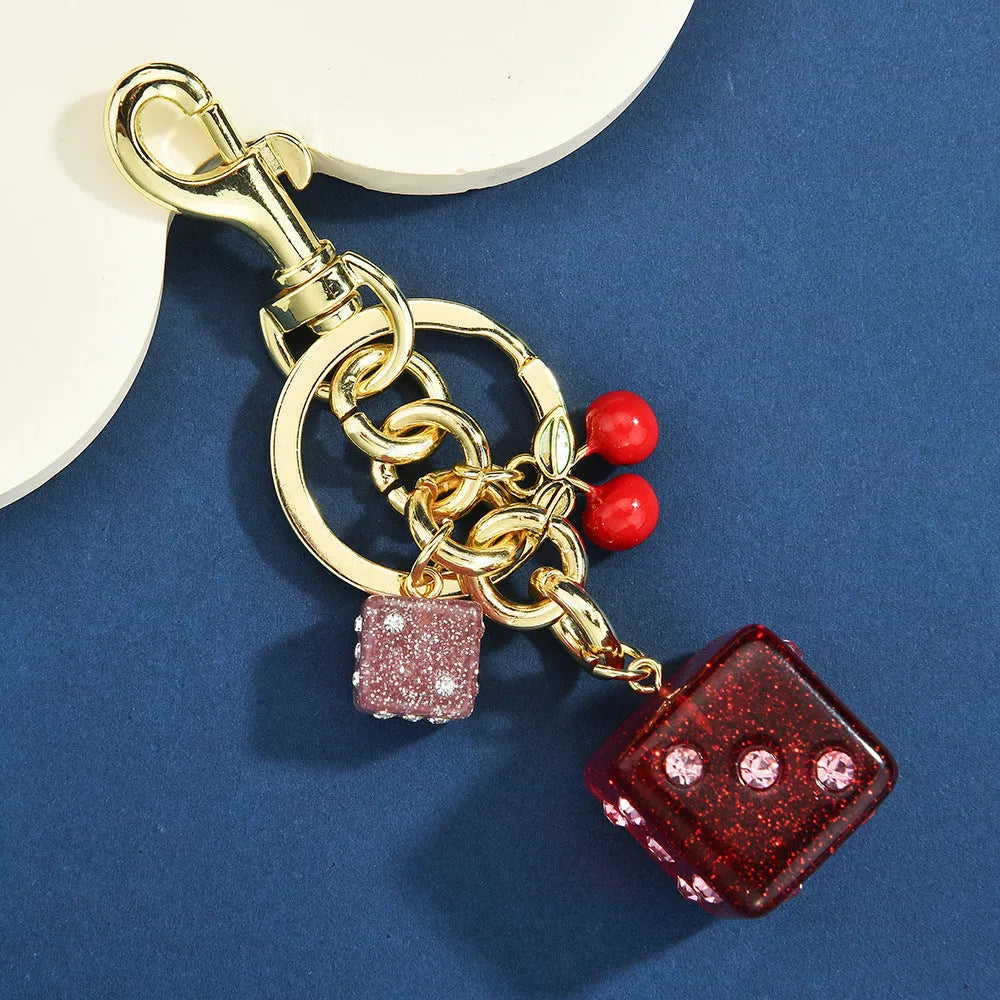 Square metal keychain pendant with a vintage two-tone cherry dice pattern.