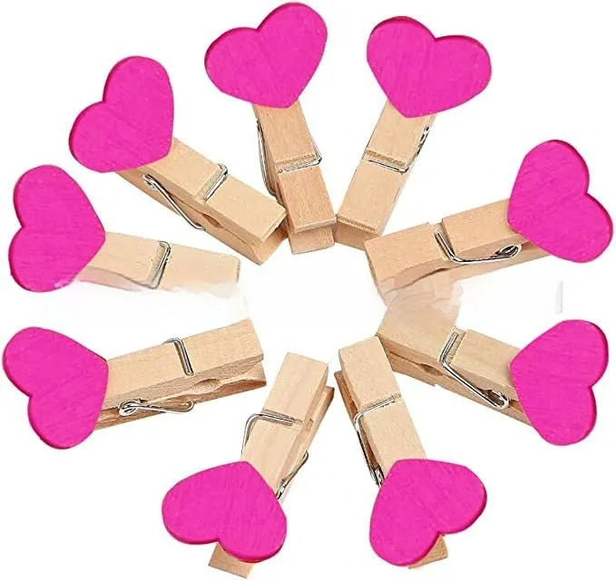 Set of five small red, pink, and white solid wood heart-shaped clips on a surface.