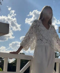 Loose fit white lace cardigan with black three-dimensional flower trim and a V-neck.