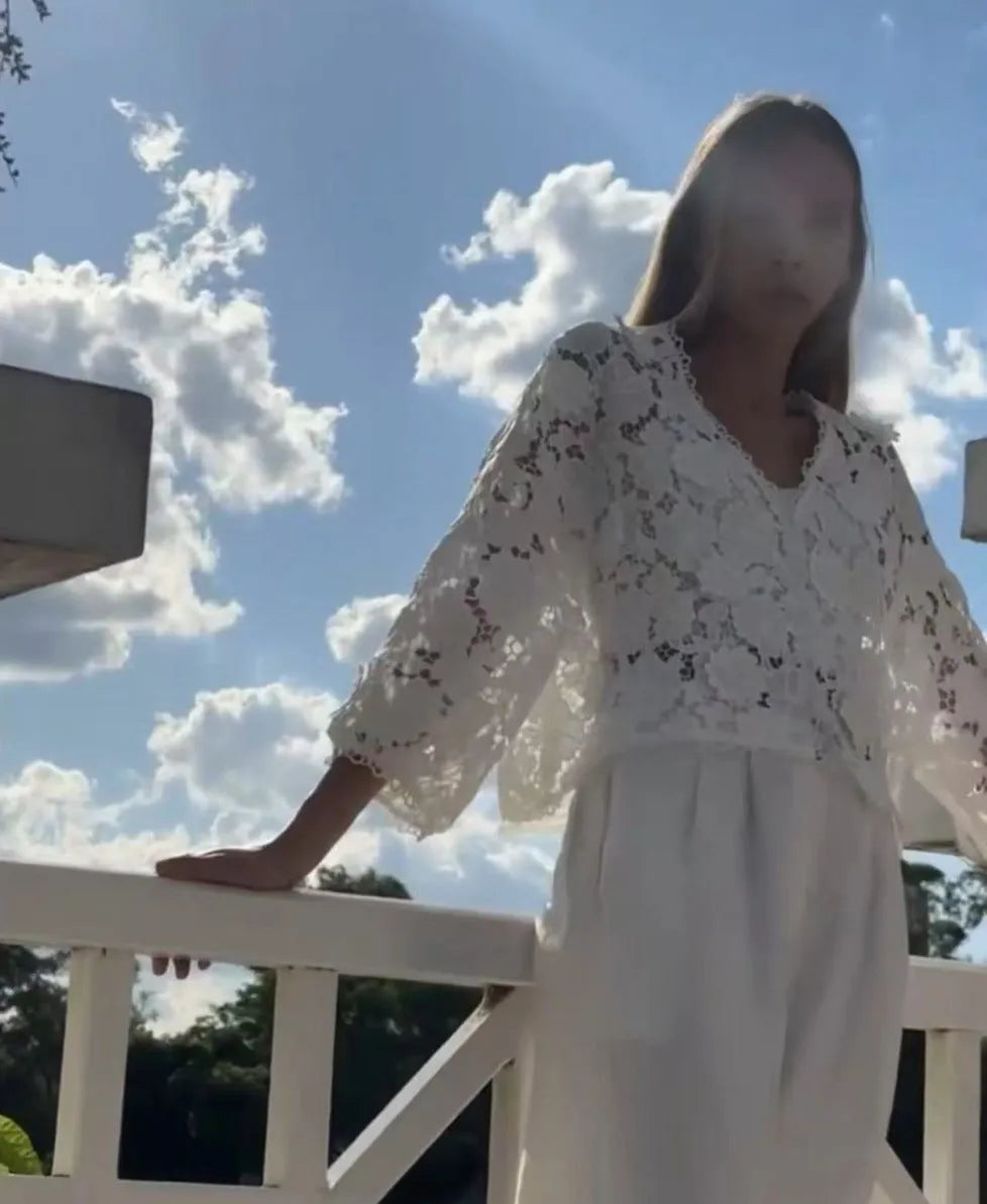 Loose fit white lace cardigan with black three-dimensional flower trim and a V-neck.
