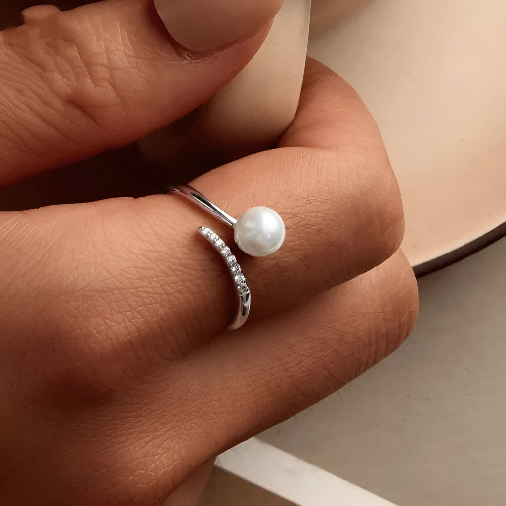 Silver adjustable open loop ring with shell pearls on white background