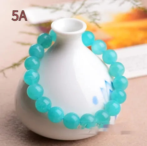 Natural blue-green Amazonite scattered loose beads in various sizes next to a finished crystal bracelet.