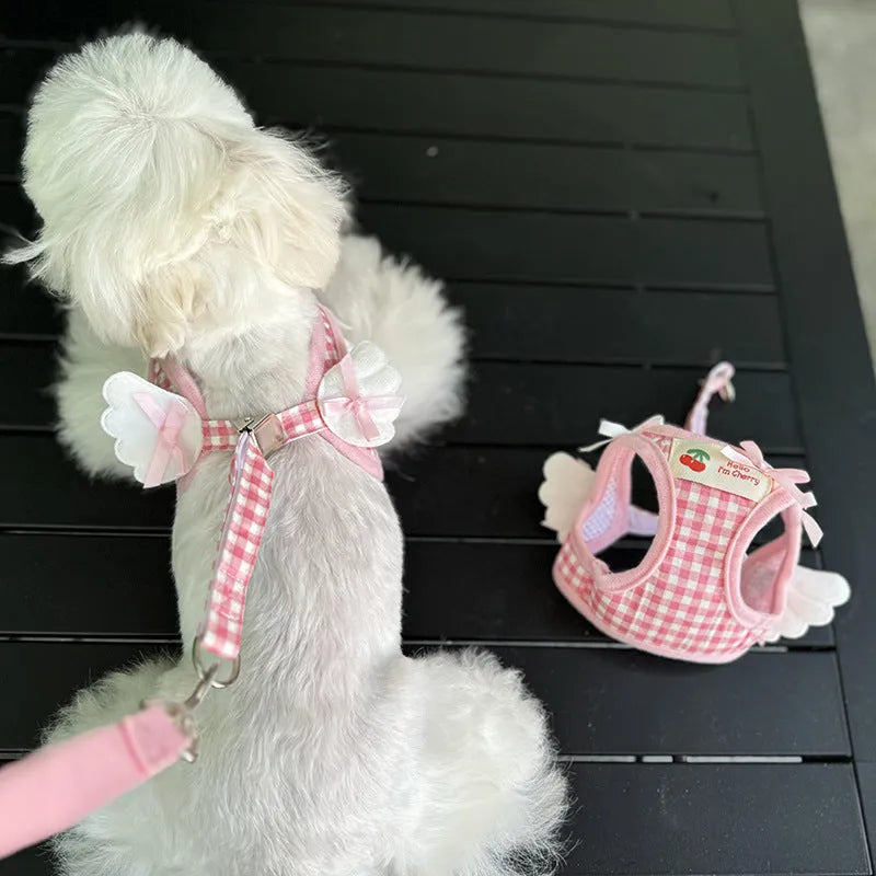 A pink cotton chest and back harness with a hand holding rope for a small dog.
