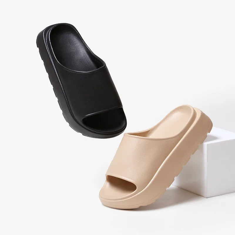 Women's beige thick-soled beach slippers with a fish mouth design on a wooden floor.