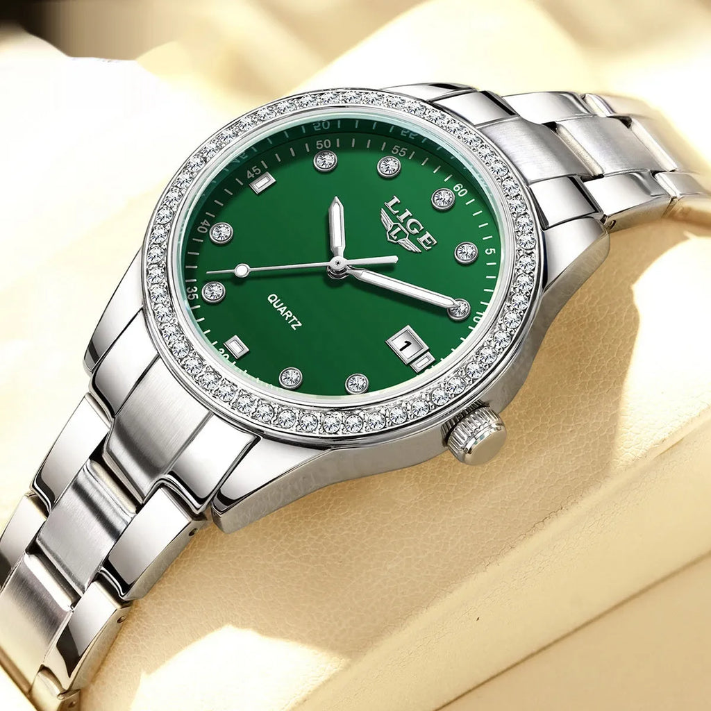 Women's silver and green quartz watch with diamond bezel, luminous hands, on a wrist.