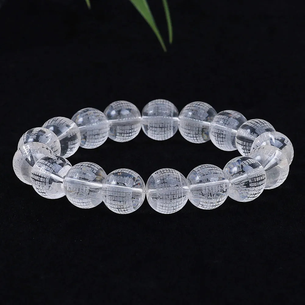 Ten 10mm round crystal prayer beads with Heart Sutra design, polished glass finish, scattered on a surface.