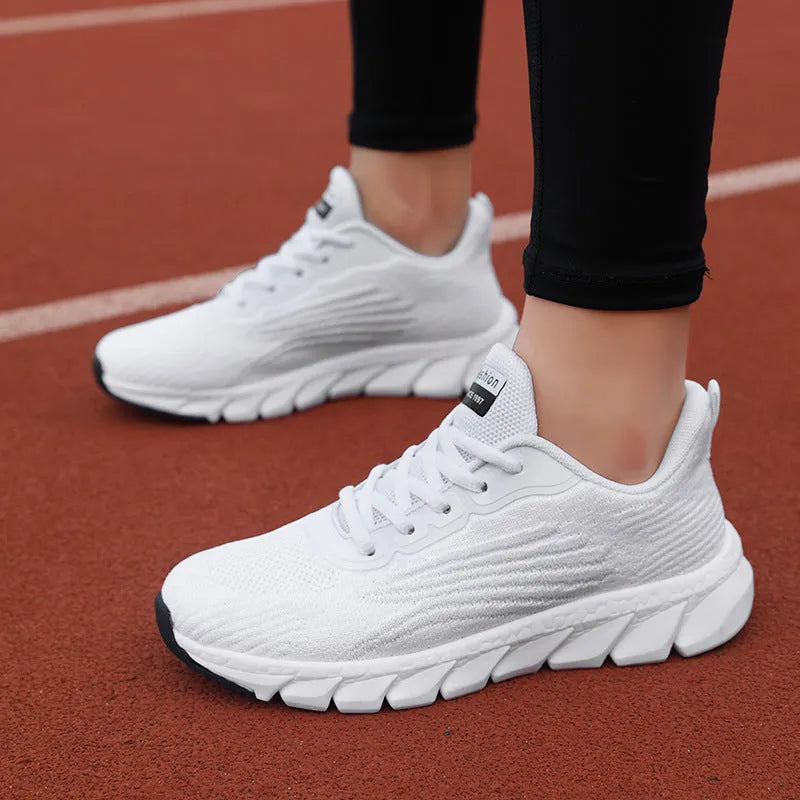 Women's low-top flat sneakers with cross-strap design in black and white colours