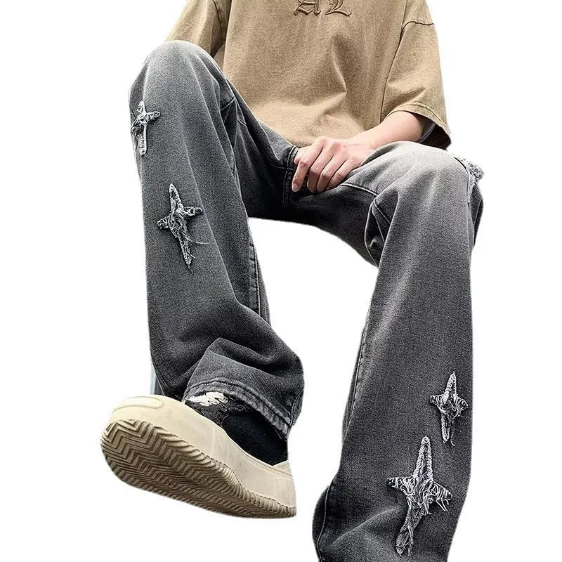 Men's loose denim trousers in black, straight-leg style with zipper fly, lying flat on a surface