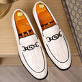 Men's casual leather shoes with embossed horsebit buckle in black, side view showing flat wedge heel and rubber sole