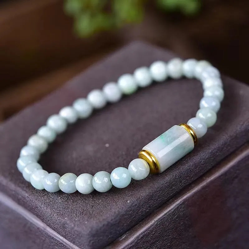 Close-up of a geometric jade bracelet with round emerald-coloured beads on a wrist.