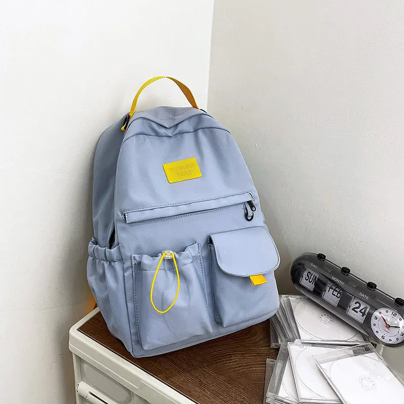 Nylon backpack school bag for junior high students, waterproof, lightweight, available in black, blue, pink, and white colours