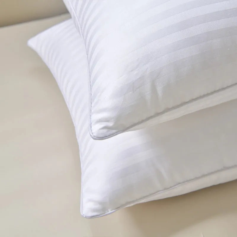 White cotton satin stripe feather and cotton pillow shown in a simple style on a bed.