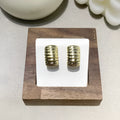 Pair of simple exaggerated C-shaped earrings in gold tone with polished finish on light background