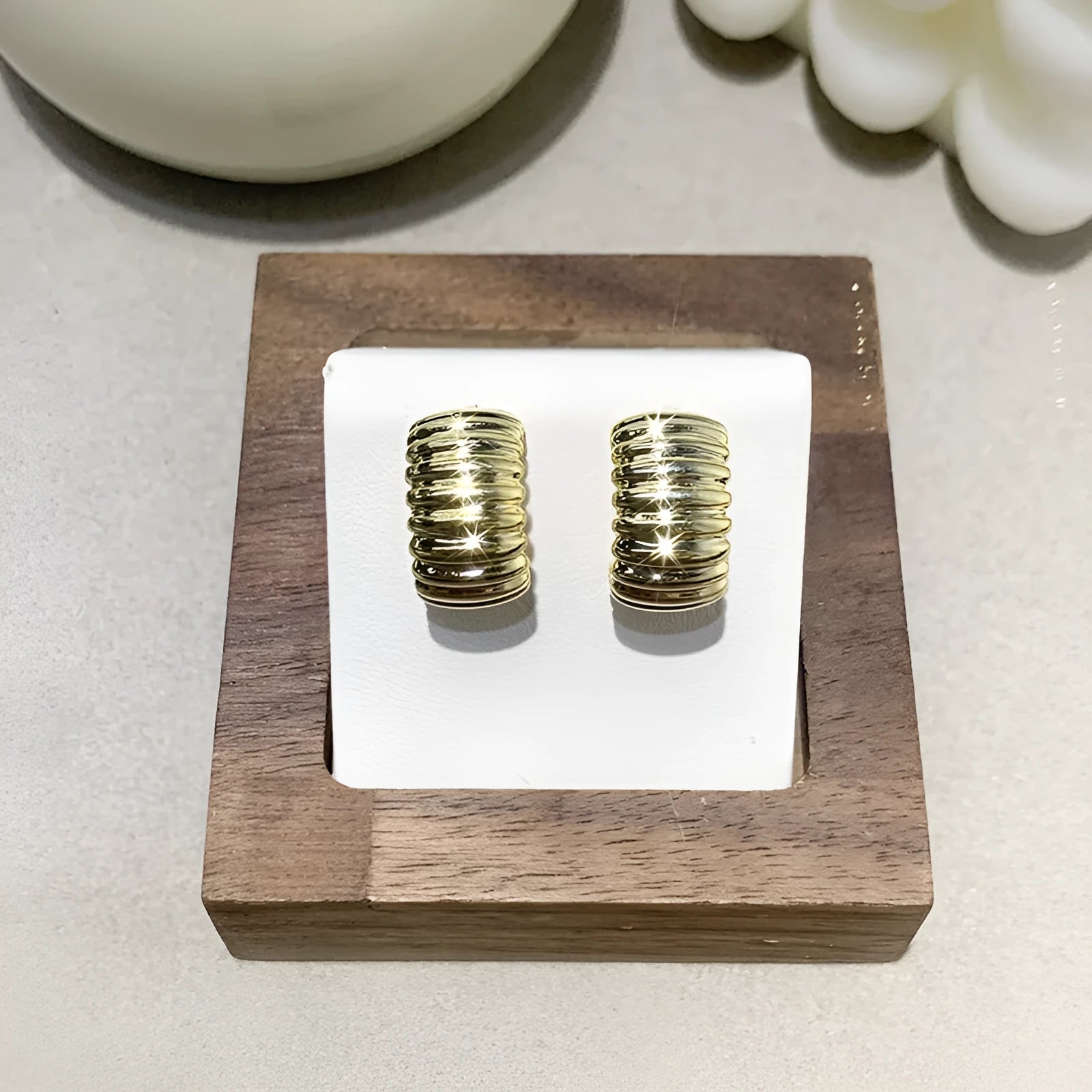 Pair of simple exaggerated C-shaped earrings in gold tone with polished finish on light background