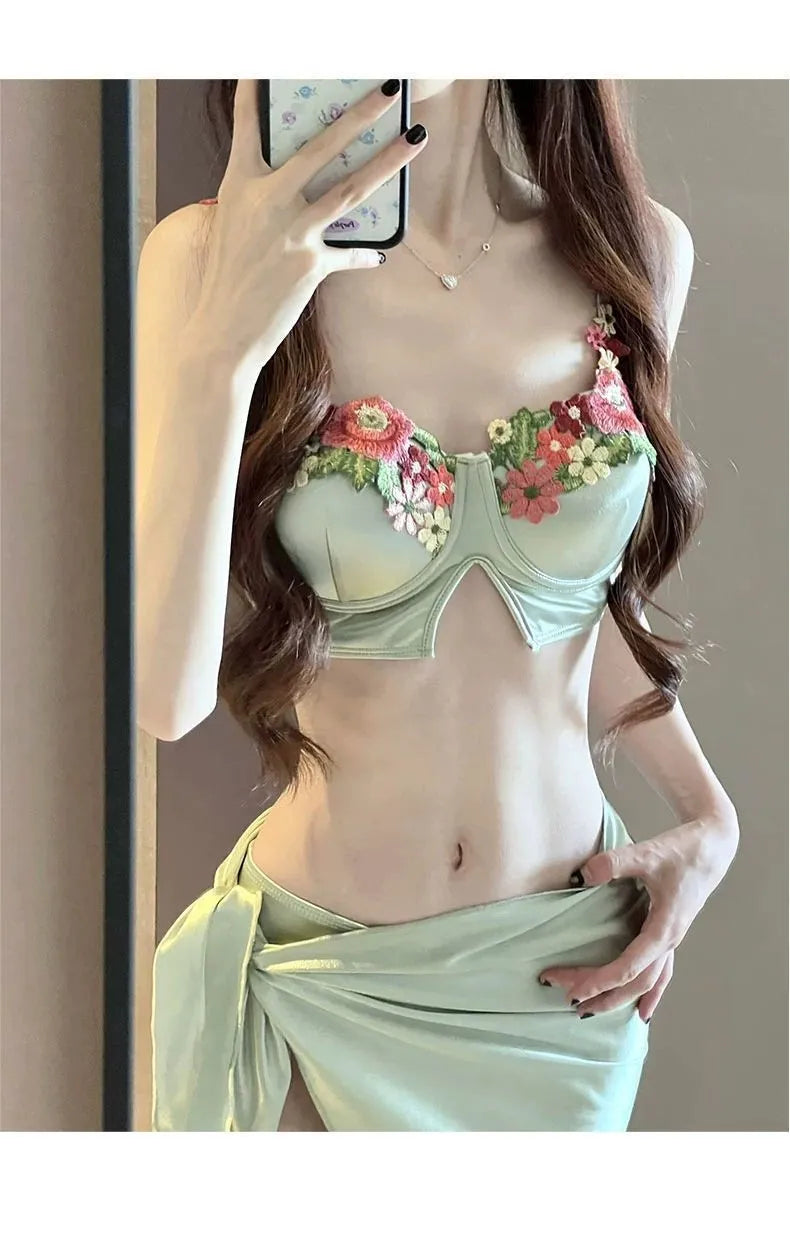 Green women's three-piece bikini set showing triangle top, briefs, and removable skirt laid flat.
