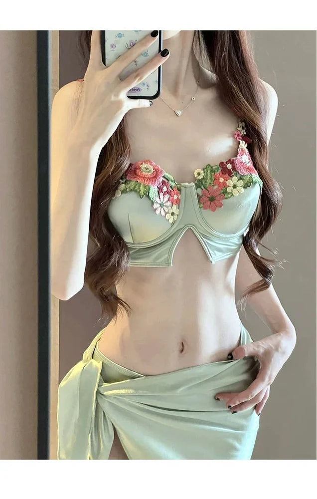 Green three-piece women's bikini set with triangle top, briefs, and coordinating skirt on mannequin