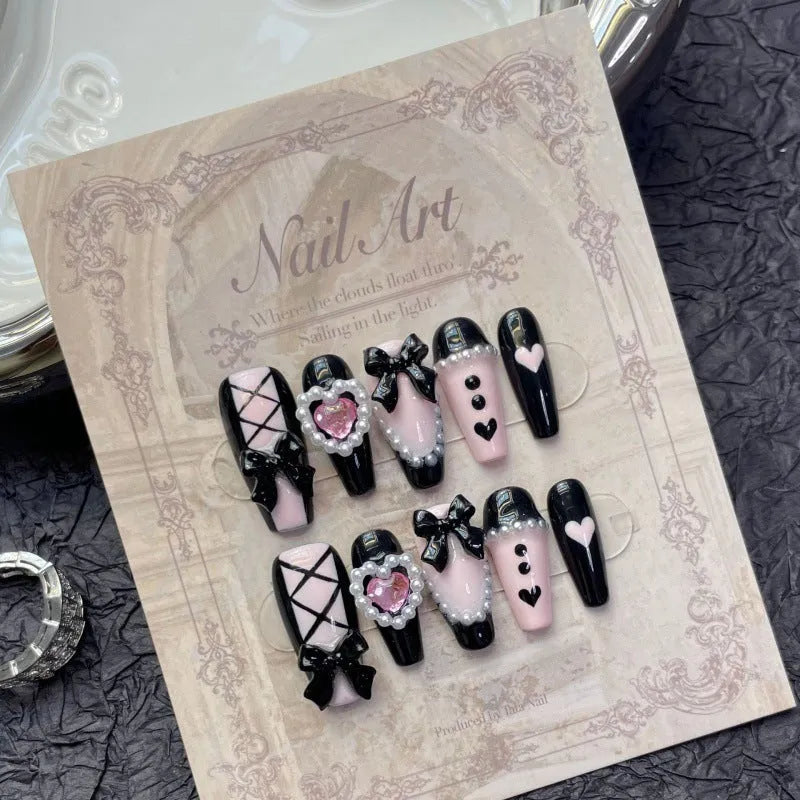 Black and pink heart pattern press-on nails with hand-painted bow decoration in cat's eye finish