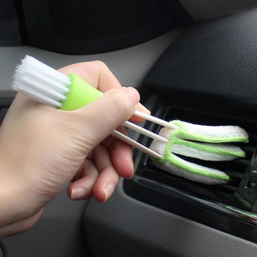 A black car air vent cleaning brush with soft bristles and a microfiber towel end for thorough vent cleaning.