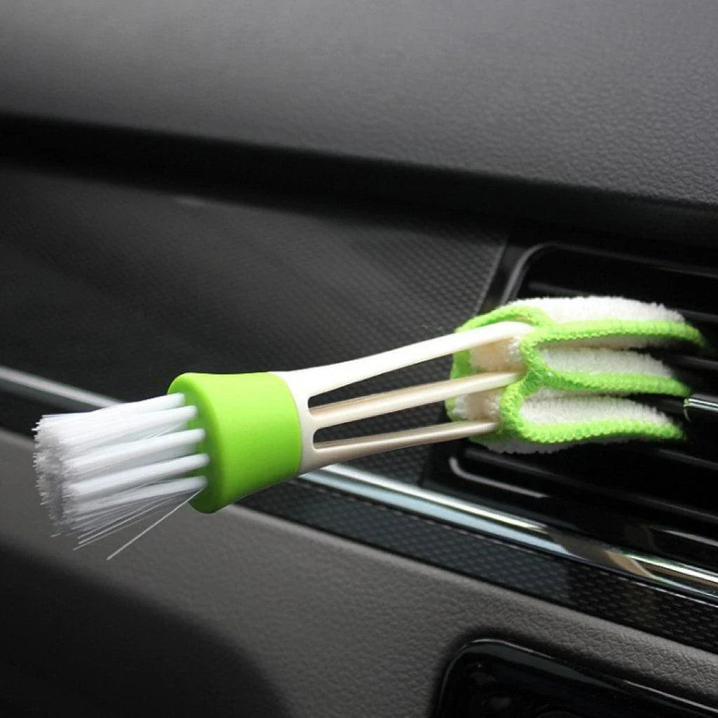 A black car air vent cleaning brush with soft bristles and a microfiber towel end for thorough vent cleaning.