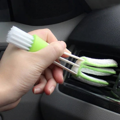 A black car air vent cleaning brush with soft bristles and a microfiber towel end for thorough vent cleaning.