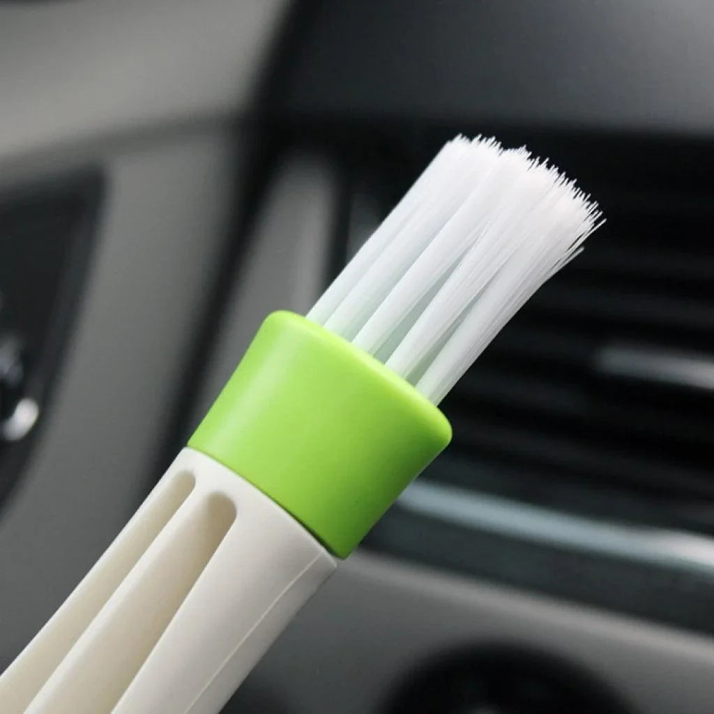 A black car air vent cleaning brush with soft bristles and a microfiber towel end for thorough vent cleaning.