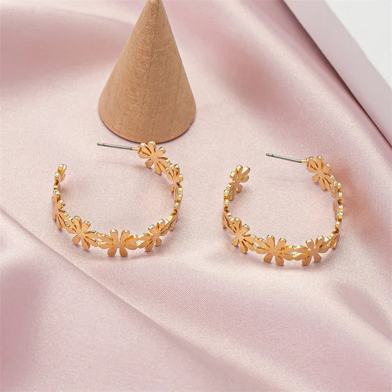 A pair of golden geometric c-shaped flower drop earrings, a timeless New Zealand fashion accessory