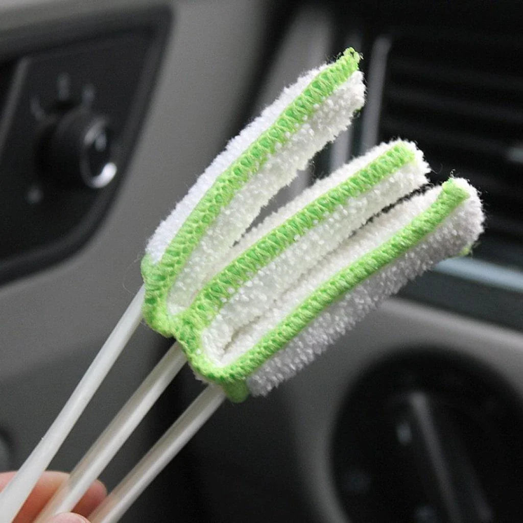 A black car air vent cleaning brush with soft bristles and a microfiber towel end for thorough vent cleaning.