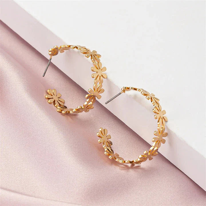 A pair of golden geometric c-shaped flower drop earrings, a timeless New Zealand fashion accessory